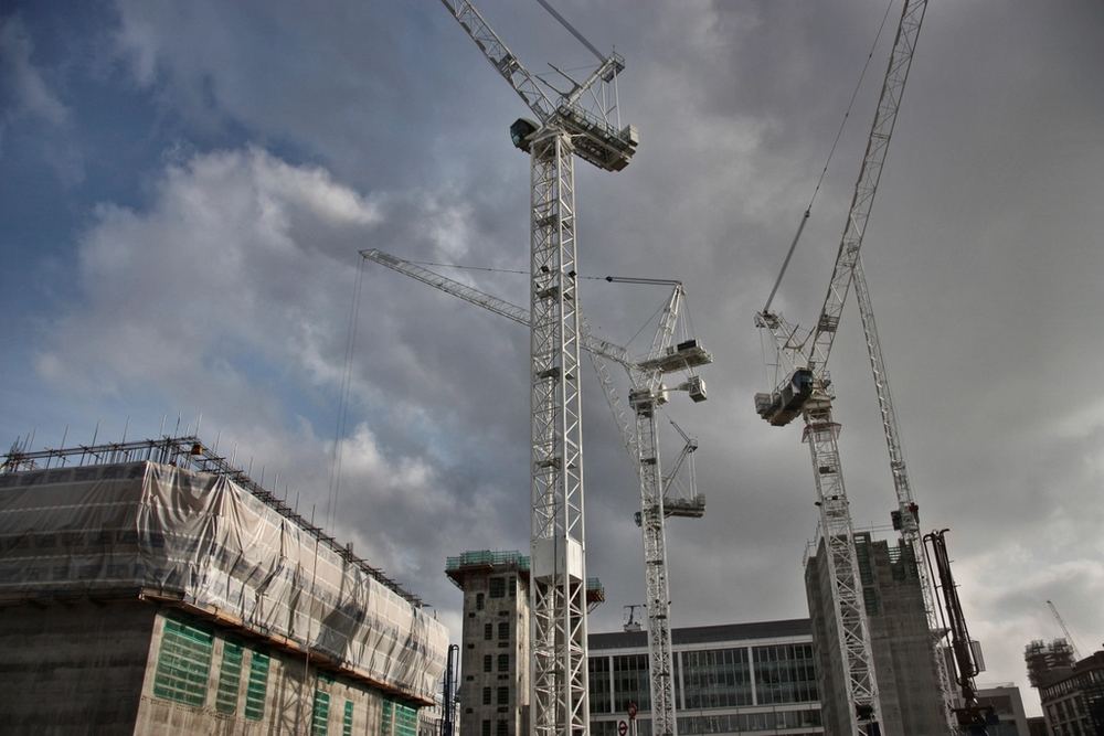 Vier Turmdrehkrane über der Baustelle vor bewölktem Himmel