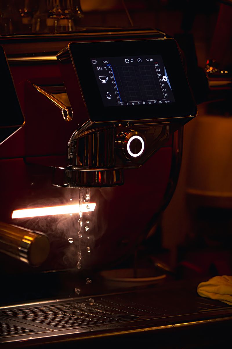 Siebträgermaschine in dunklem Raum, ein Espressostrahl läuft in die Tasse.