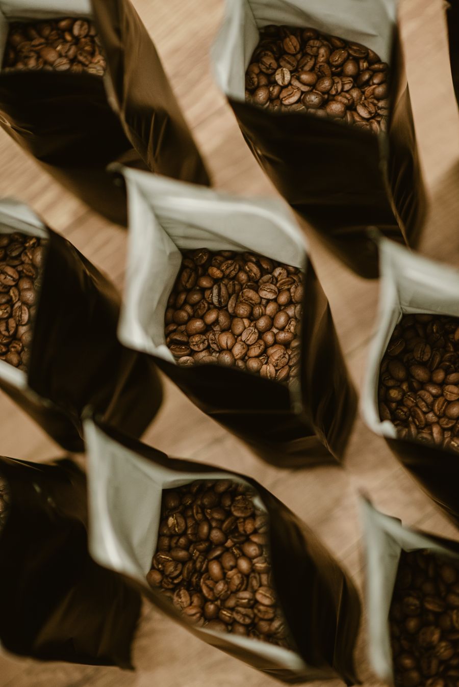 Eine Reihe geöffneter Tüten mit gerösteten Kaffeebohnen von oben.