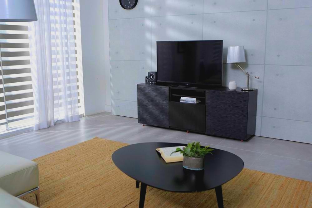 Minimalistischer Wohnraum mit Sichtbetonwand, niedrigem Tisch und Holzboden